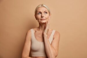 woman touches skin after applying anti age cream concentrated with thoughtful expression wears cropped top isolated brown 273609 49263 Non-Surgical Face Lift